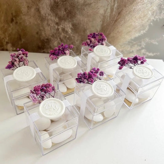 Boîte de dragées violettes élégante avec fleurs séchées, ruban blanc et sceau en cire personnalisé