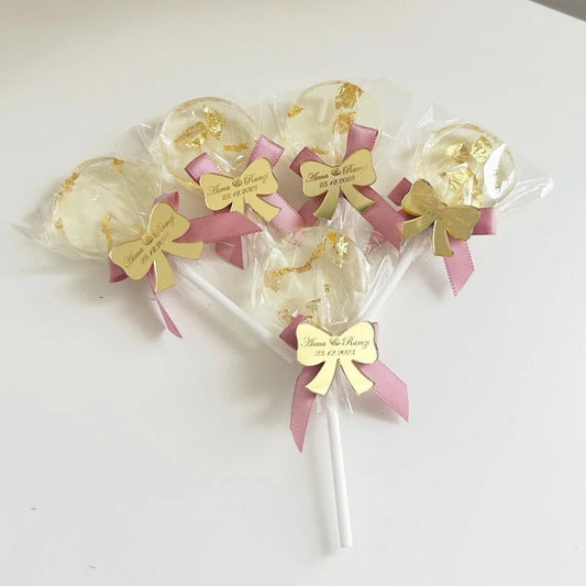 Sucette Minnie Rose avec feuille d’or comestible et étiquette en plexiglas doré en forme de nœud
