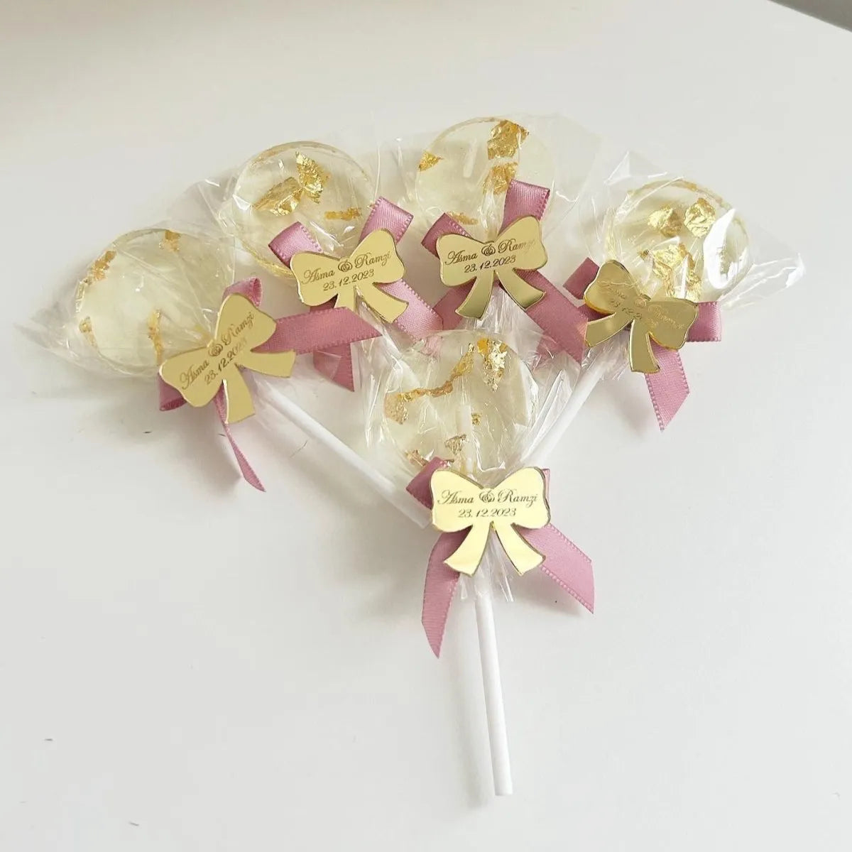 Sucette Minnie Rose avec feuille d’or comestible et étiquette en plexiglas doré en forme de nœud