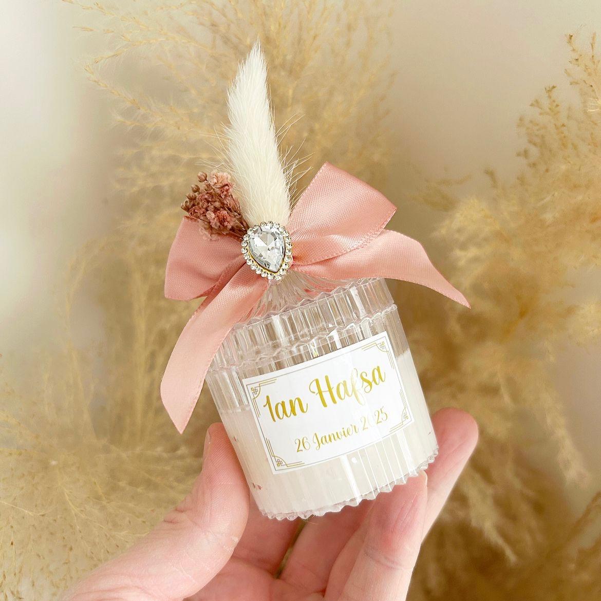 Bougie cadeau invité Queen avec nœud rose, plume blanche et strass, personnalisée avec prénoms et date.