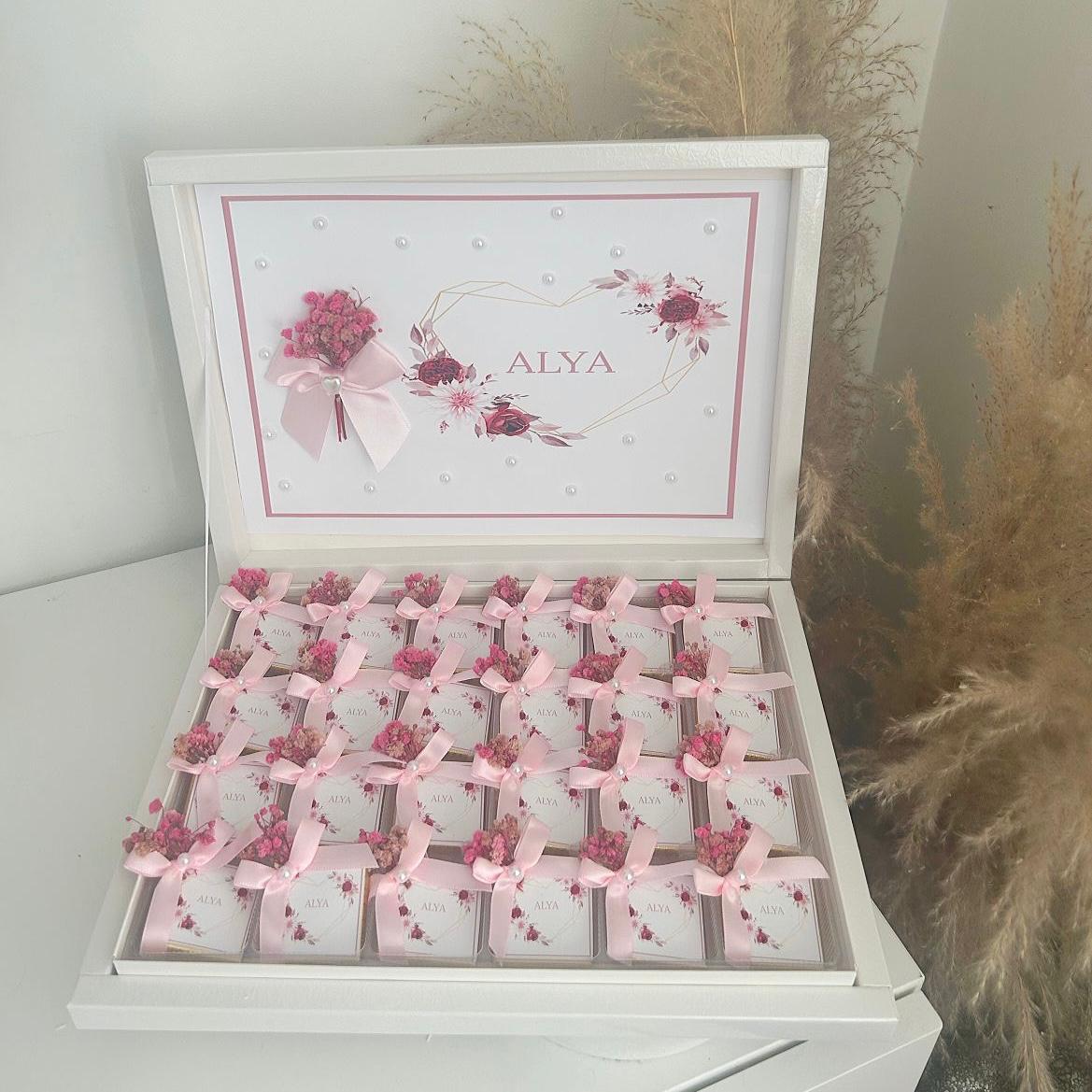 Cadeau invité baby shower : box chocolat thème rose, avec boîtes individuelles personnalisées et rubans satinés.