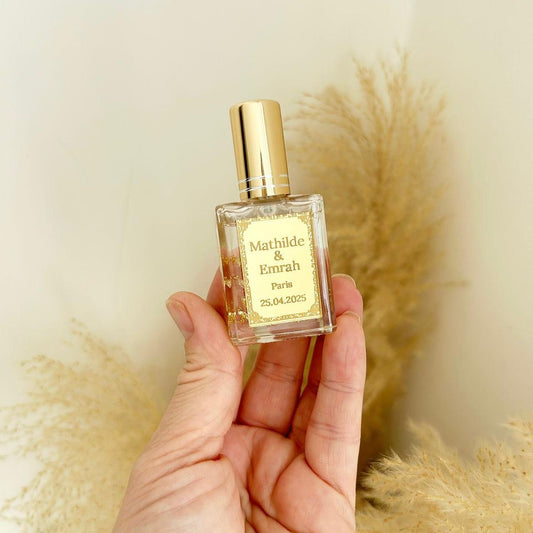 Cadeau invité : mini parfum Dubai avec capuchon doré, flacon transparent et étiquette personnalisée prénoms, ville et date.