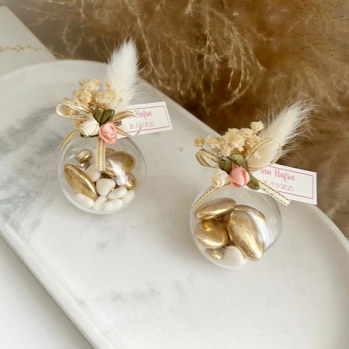 Cadeau invité : boule de dragées Vintage en plexi avec décoration bohème (plume, fleurs, rubans) et personnalisation.