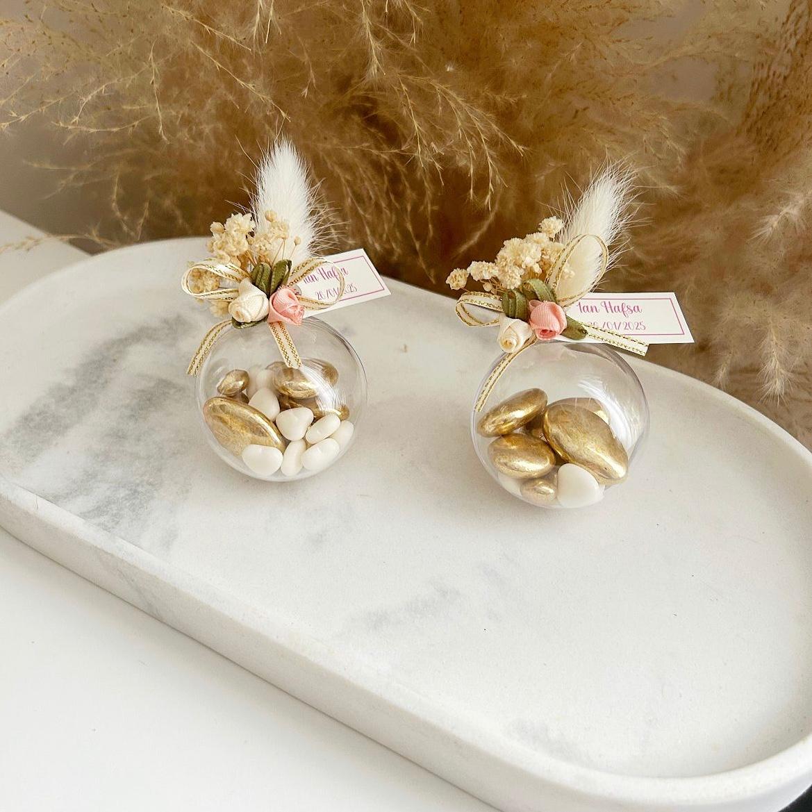 Cadeau invité : boule de dragées Vintage en plexi avec décoration bohème (plume, fleurs, rubans) et personnalisation.