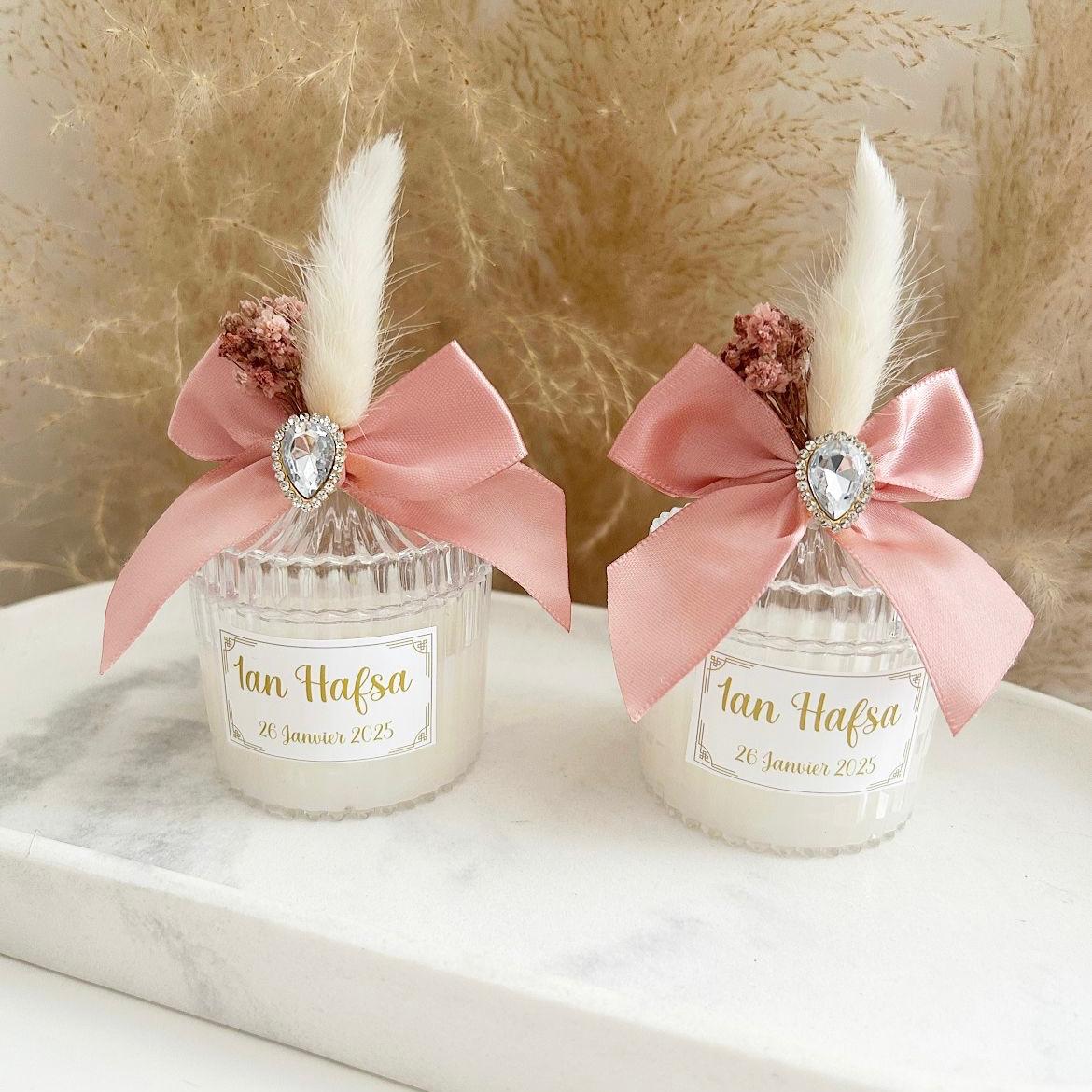 Bougie cadeau invité Queen avec nœud rose, plume blanche et strass, personnalisée avec prénoms et date.