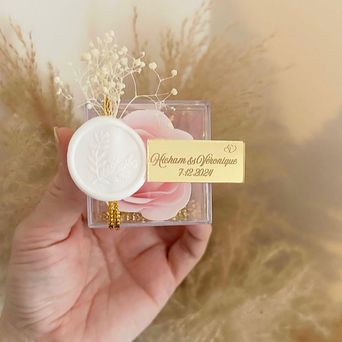 Cadeau invité : rose de savon Soélia rose en boîte plexi avec sceau blanc, fleurs séchées et plaque dorée personnalisée.