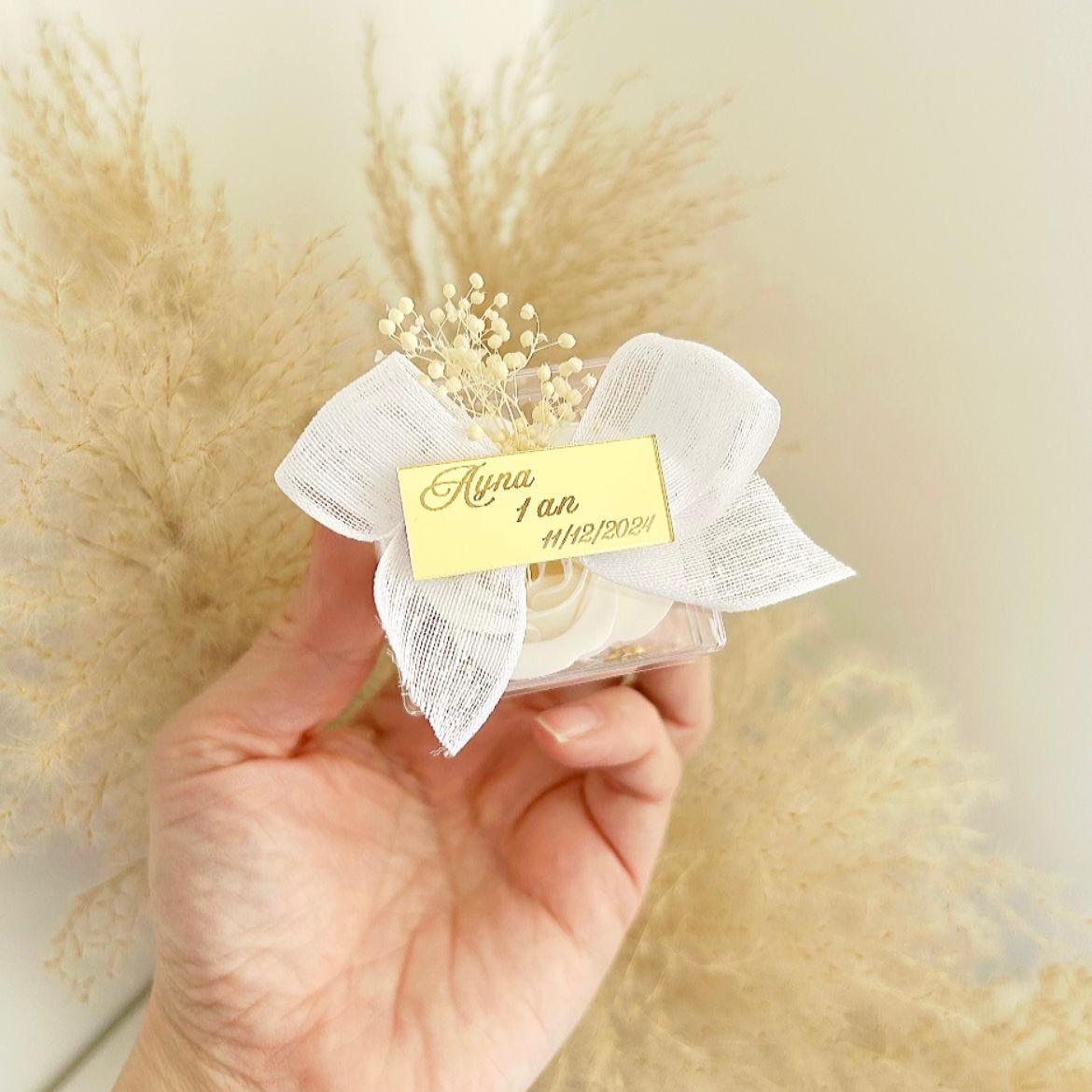 Lot de roses de savon Angelita en boîtes transparentes, décorées de gypsophile, avec nœud en ruban blanc et plaque dorée personnalisée, présentées sur un plateau.