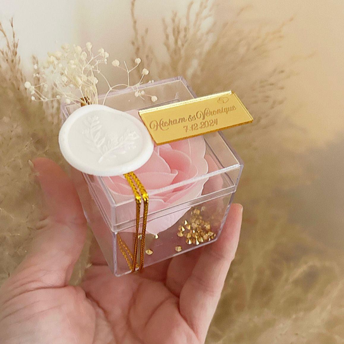 Cadeau invité : rose de savon Soélia rose en boîte plexi avec sceau blanc, fleurs séchées et plaque dorée personnalisée.